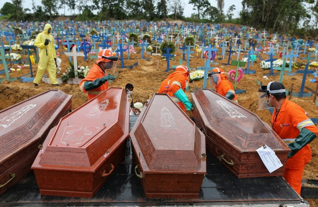 Caixões com vítimas da covid-19 são descarregados para serem enterrados em uma vala comum no cemitério de Nossa Senhora da Piedade, em Manaus. Foto Michael Dantas/AFP